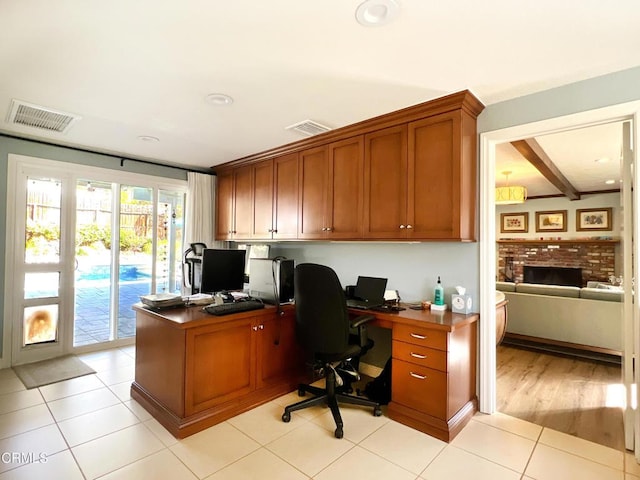 office with visible vents, a fireplace, beamed ceiling, and light tile patterned flooring