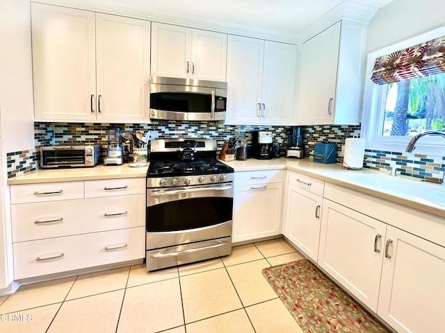 kitchen with light tile patterned floors, appliances with stainless steel finishes, light countertops, and a sink