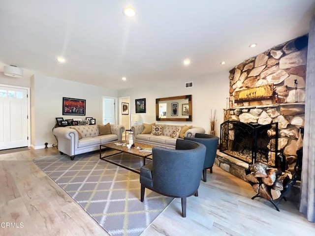 living room with recessed lighting, visible vents, a fireplace, and wood finished floors