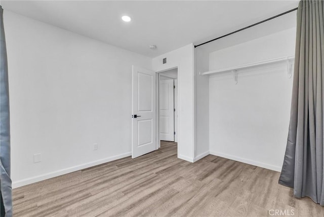 unfurnished bedroom with light wood-style floors, baseboards, a closet, and recessed lighting