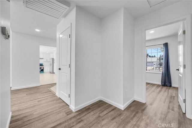 hall featuring visible vents, baseboards, and wood finished floors