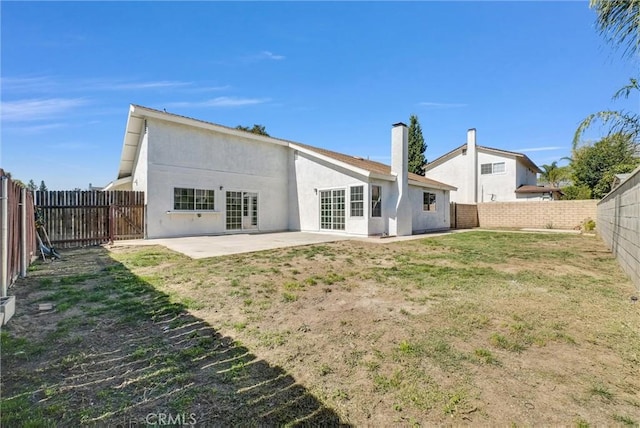 back of house with a fenced backyard, a patio, a lawn, and stucco siding