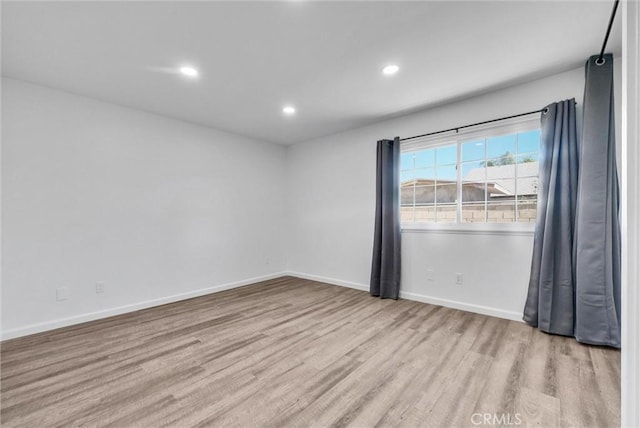 spare room featuring recessed lighting, wood finished floors, and baseboards