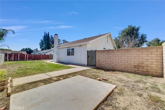 exterior space with stucco siding, a fenced backyard, a patio, and a lawn