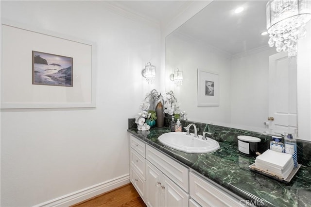 bathroom featuring baseboards, ornamental molding, wood finished floors, and vanity