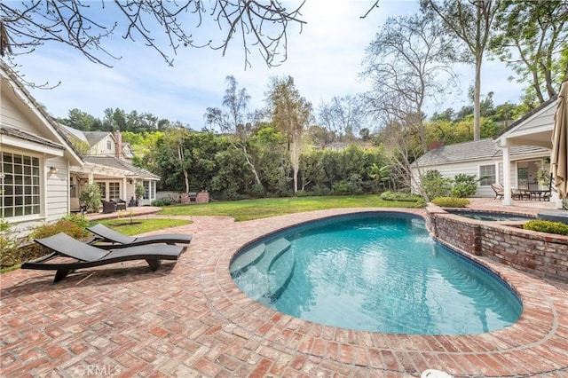 outdoor pool with an in ground hot tub and a patio area