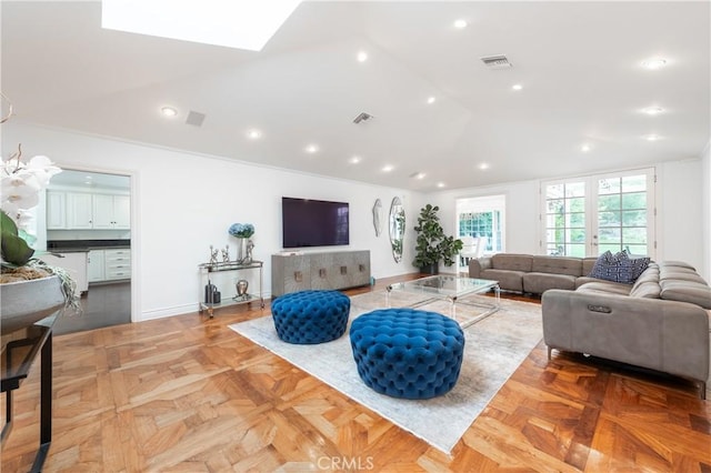 living area featuring vaulted ceiling with skylight, recessed lighting, visible vents, and baseboards