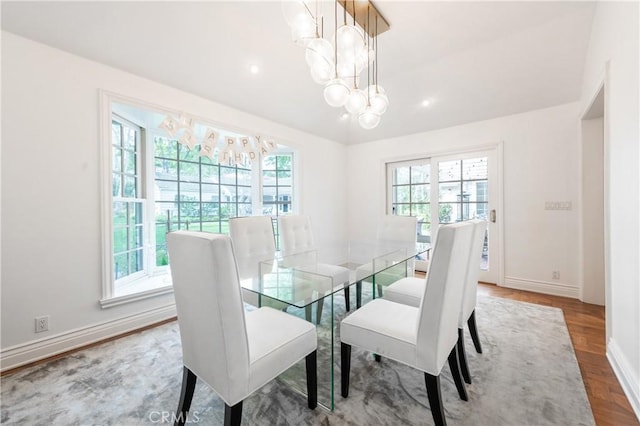 dining space featuring baseboards, lofted ceiling, wood finished floors, a chandelier, and recessed lighting