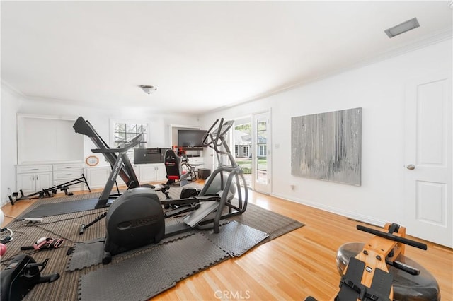 workout area featuring ornamental molding, baseboards, and wood finished floors