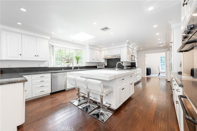 kitchen featuring visible vents, white cabinets, dishwasher, ornamental molding, and under cabinet range hood