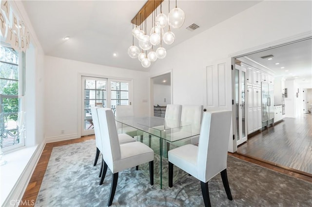 dining room featuring visible vents, vaulted ceiling, an inviting chandelier, and wood finished floors