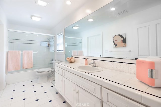 full bathroom with toilet, visible vents, bath / shower combo with glass door, and vanity