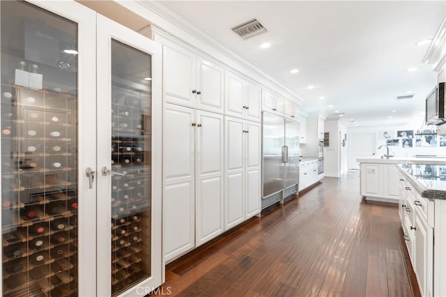 interior space featuring visible vents, white cabinets, dark wood-type flooring, stainless steel built in refrigerator, and recessed lighting