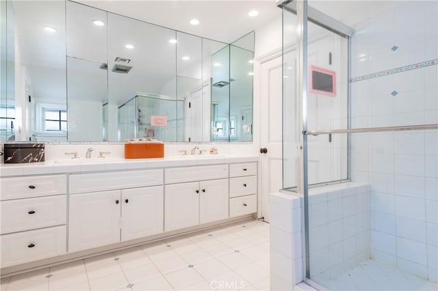 bathroom with double vanity, a shower stall, a sink, and recessed lighting