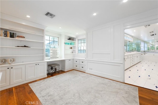 interior space featuring built in desk, wood finished floors, and visible vents