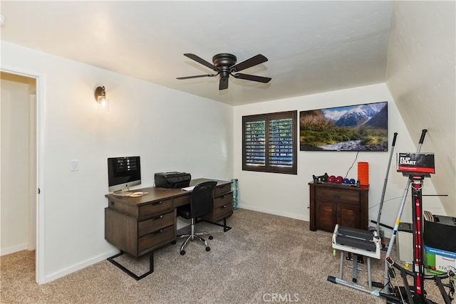 carpeted office space featuring a ceiling fan and baseboards