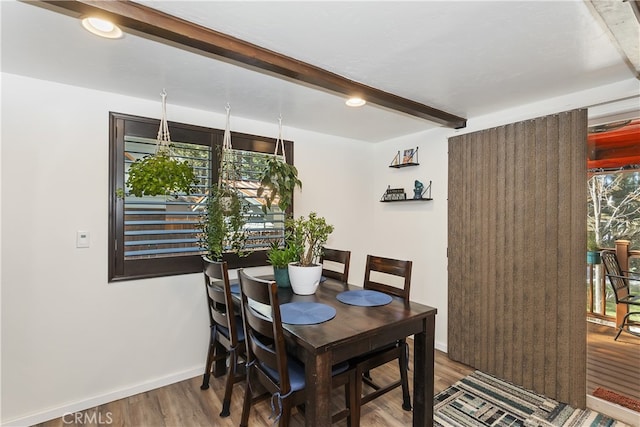 dining room featuring wood finished floors, beam ceiling, and baseboards