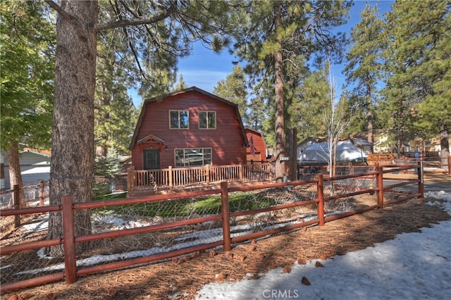 view of front of home with fence, a wooden deck, and a gambrel roof