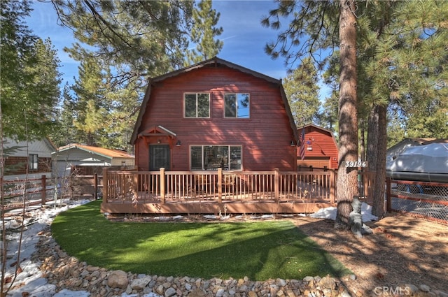 back of house featuring a wooden deck, a yard, fence, and a gambrel roof