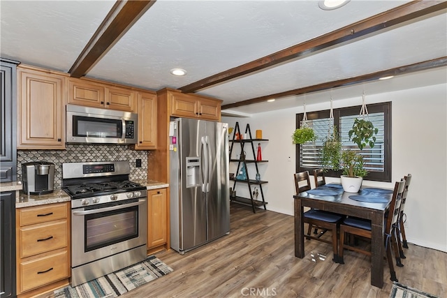 kitchen featuring stainless steel appliances, beamed ceiling, backsplash, and wood finished floors