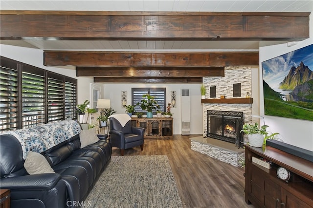 living area with a stone fireplace, beamed ceiling, and wood finished floors