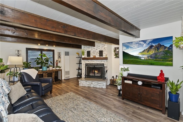 living area with a fireplace, beamed ceiling, and wood finished floors