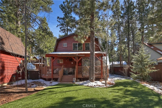 rear view of house with fence, a wooden deck, a gambrel roof, and a lawn