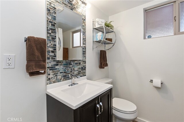 bathroom featuring vanity, backsplash, and toilet