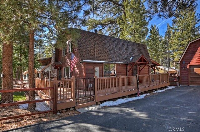 view of front of property featuring an outbuilding, a shingled roof, and a wooden deck