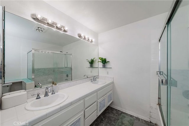 bathroom with a shower with door, a sink, and double vanity