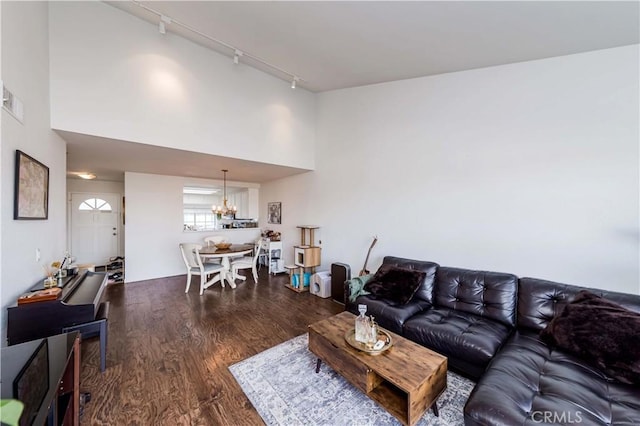 living area featuring high vaulted ceiling, rail lighting, a notable chandelier, and wood finished floors