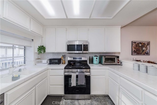 kitchen featuring appliances with stainless steel finishes, white cabinets, a toaster, and a sink