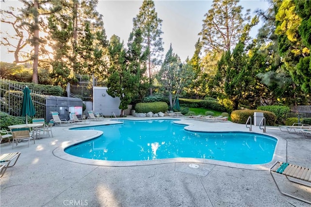 community pool with a patio and fence