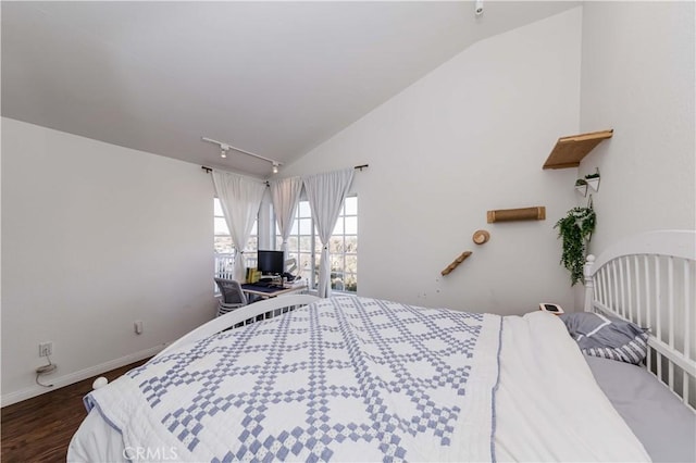 bedroom featuring rail lighting, baseboards, vaulted ceiling, and dark wood-type flooring