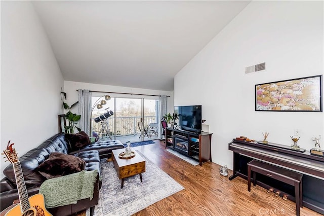 living room featuring high vaulted ceiling, wood finished floors, and visible vents