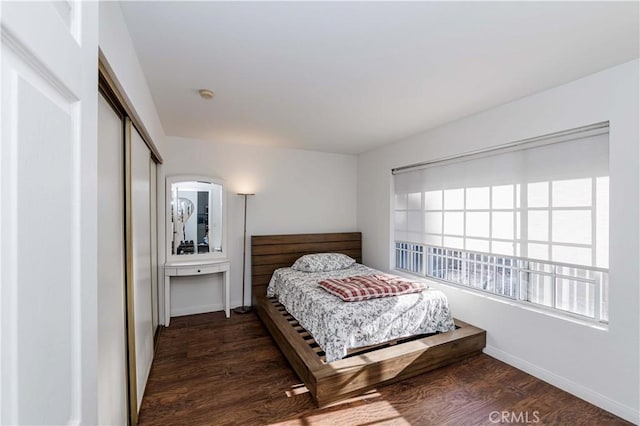 bedroom with a closet, wood finished floors, and baseboards