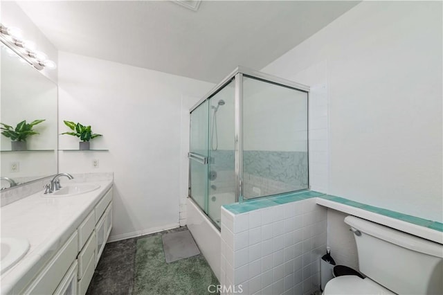 bathroom featuring double vanity, toilet, enclosed tub / shower combo, a sink, and baseboards