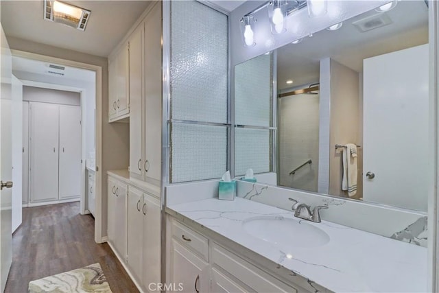 full bathroom with visible vents, walk in shower, wood finished floors, and vanity