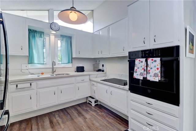 kitchen with dark wood-style flooring, light countertops, white cabinetry, a sink, and black appliances