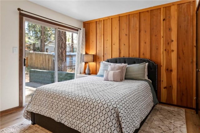 bedroom featuring access to outside, wood finished floors, and wooden walls