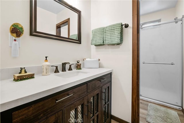 full bathroom with vanity, a shower stall, and wood finished floors