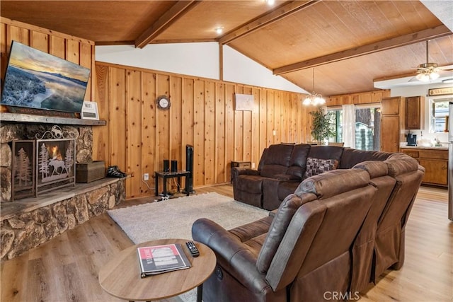 living area featuring light wood-style floors, wood walls, a fireplace, and lofted ceiling with beams