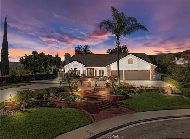 view of front of house featuring a garage, a yard, and decorative driveway