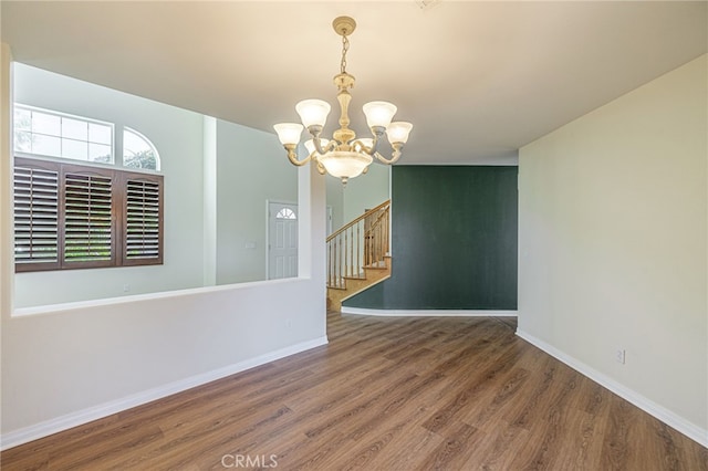 unfurnished room with a notable chandelier, stairway, baseboards, and wood finished floors