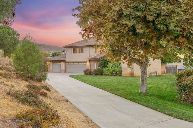 view of front of house featuring concrete driveway, a lawn, fence, and stucco siding