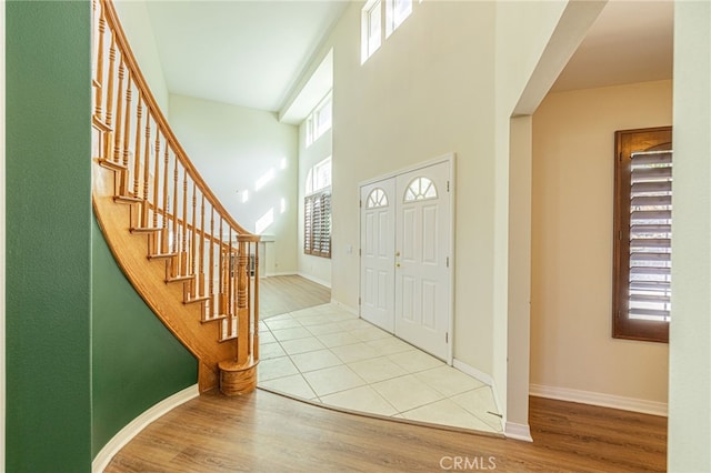 entrance foyer with stairs, a high ceiling, wood finished floors, and baseboards