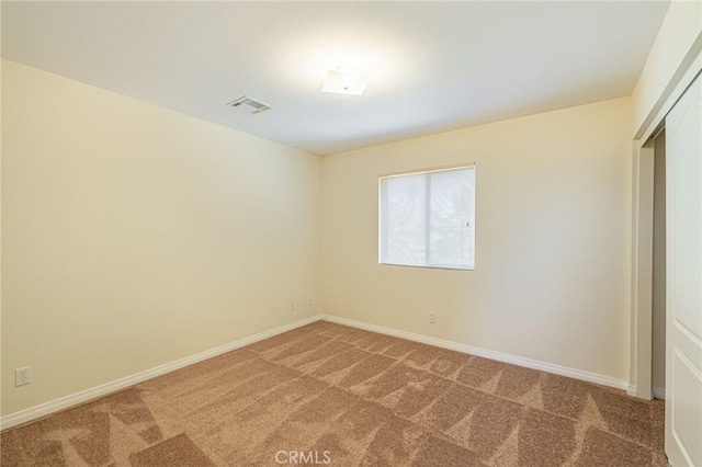 spare room with light colored carpet, visible vents, and baseboards