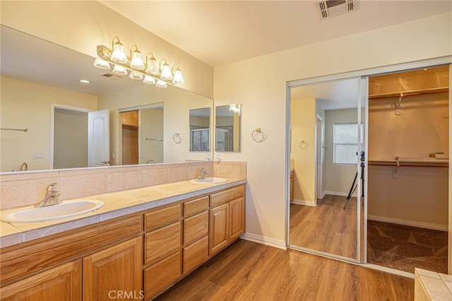 bathroom featuring double vanity, wood finished floors, a sink, and visible vents