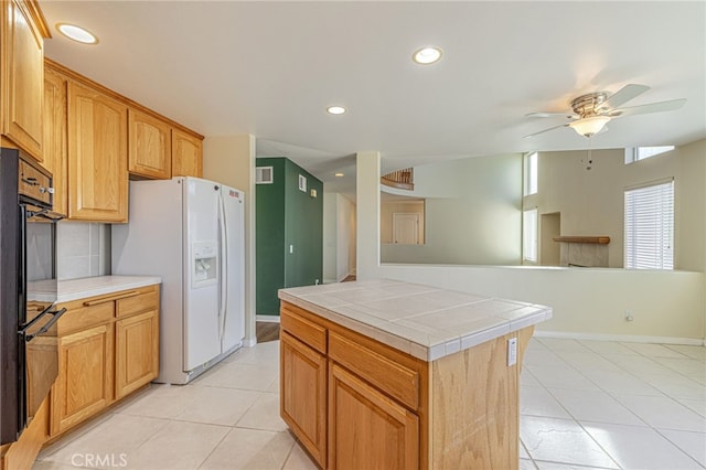 kitchen with tile countertops, ceiling fan, white refrigerator with ice dispenser, and recessed lighting