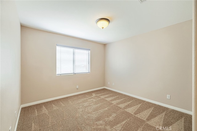 spare room featuring carpet floors and baseboards